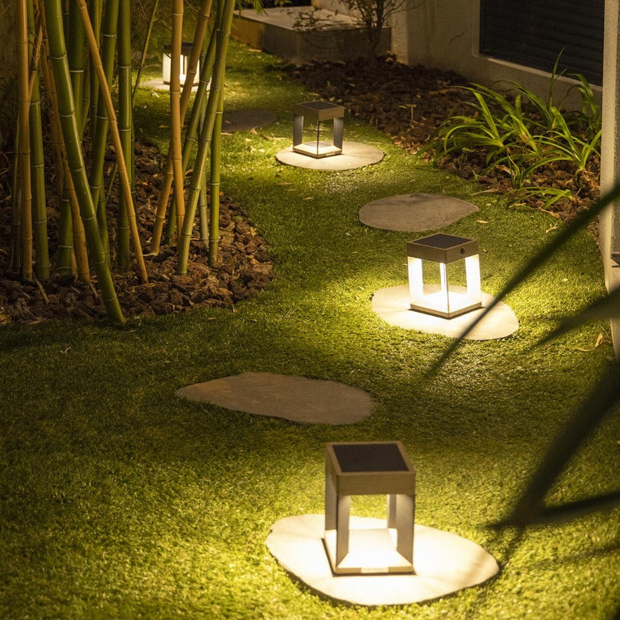 Lampe de table solaire TECKALU Les Jardins en teck et aluminium noir dans un jardin